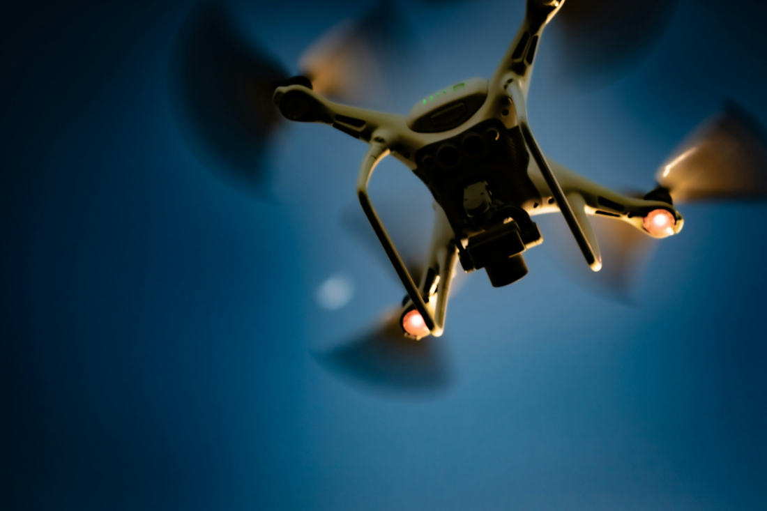 Quadcopter seen from below against a blue night sky